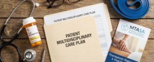 A flat-lay of a wooden desk featuring a "Patient Multidisciplinary Care Plan" file, a stethoscope, exercise bands, and an MTASA brochure, representing a team approach to pain management.